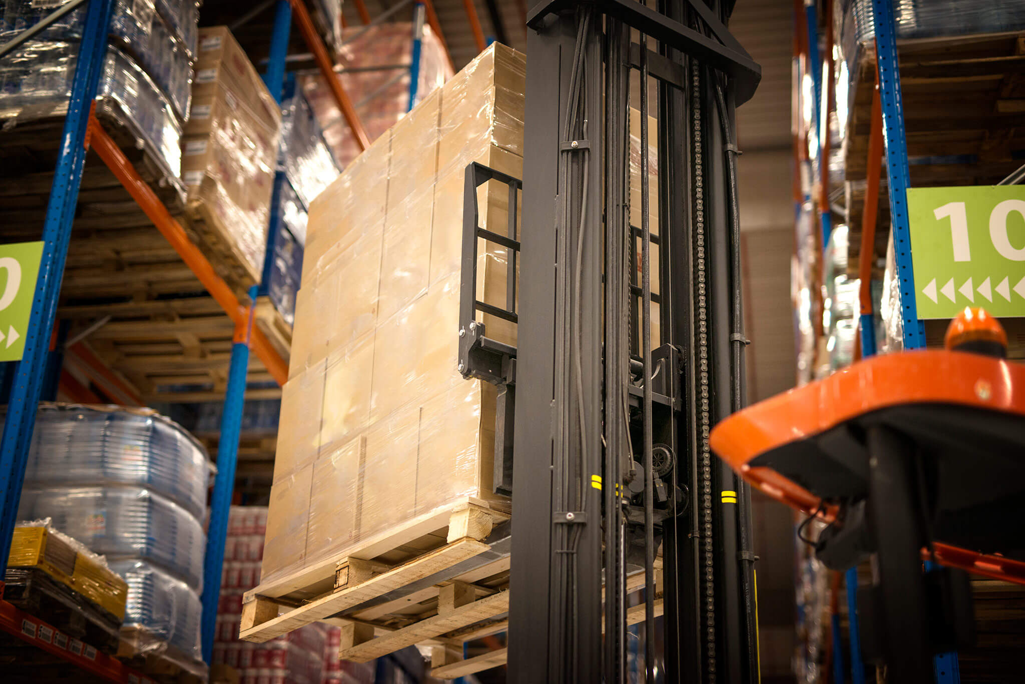 industrial-forklift-machine-lifting-palette-full-cardboard-boxes-placing-them-shelves-distribution-warehouse-facility